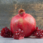 Pomegranate and pomegranate seeds on stone table. High quality photo